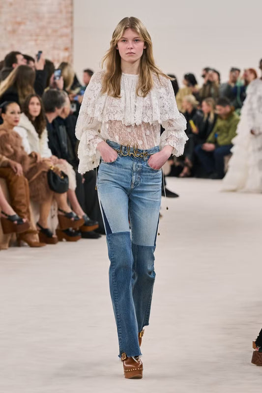 woman with lace top and jeans on a runway